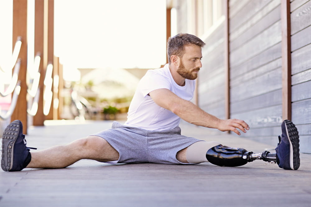 Ein Mann beim Strecken vor dem Sport trägt eine Unterschenkelprothese.