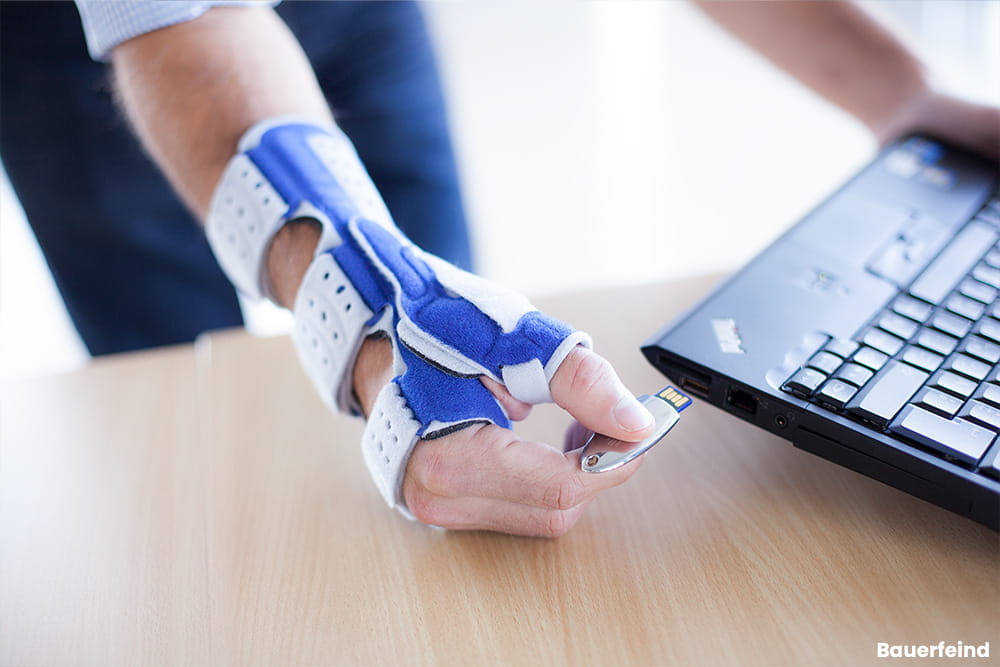 Ein Mann bei der Büroarbeit trägt dabei seine Handbandage.