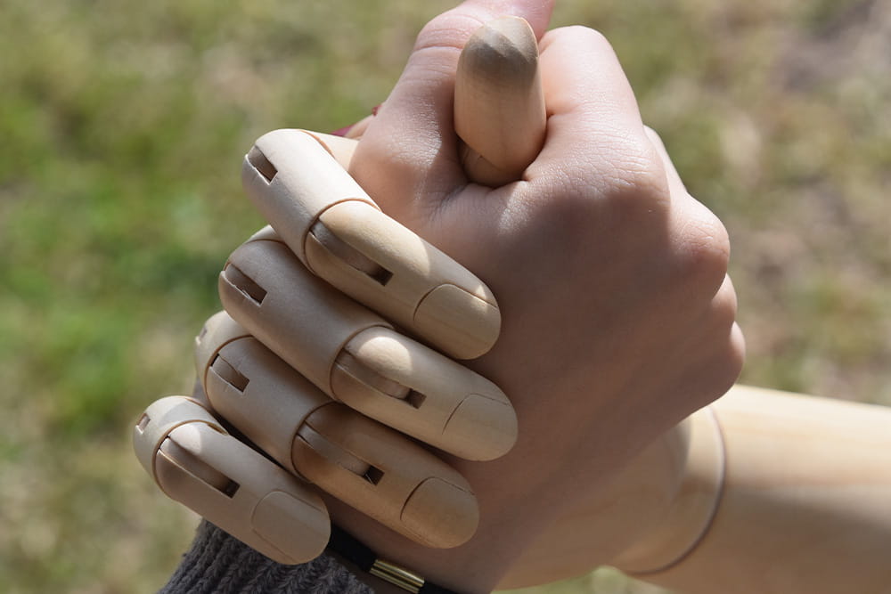 Eine Menschliche Hand umfasst kameradschaftlich eine Prothesenhand.