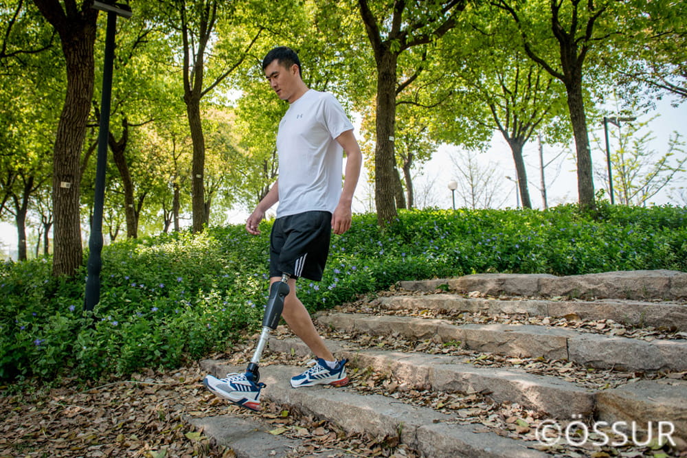 Ein Mann mit Prothese steigt Treppen in einem Park runter.